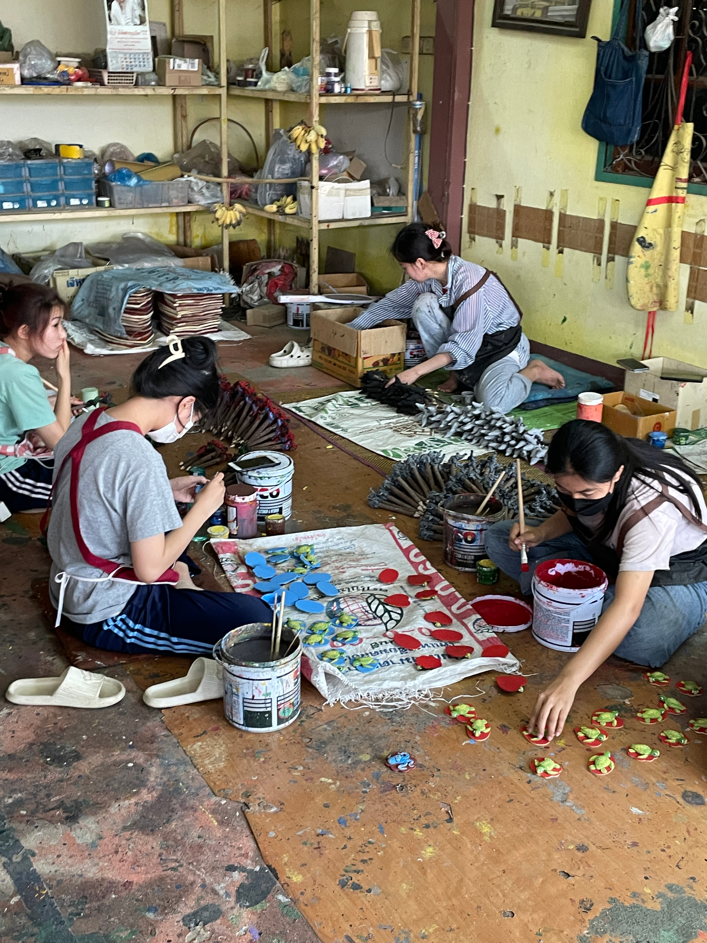 Thai artisans hand-painting wooden and ceramic pieces in a village workshop