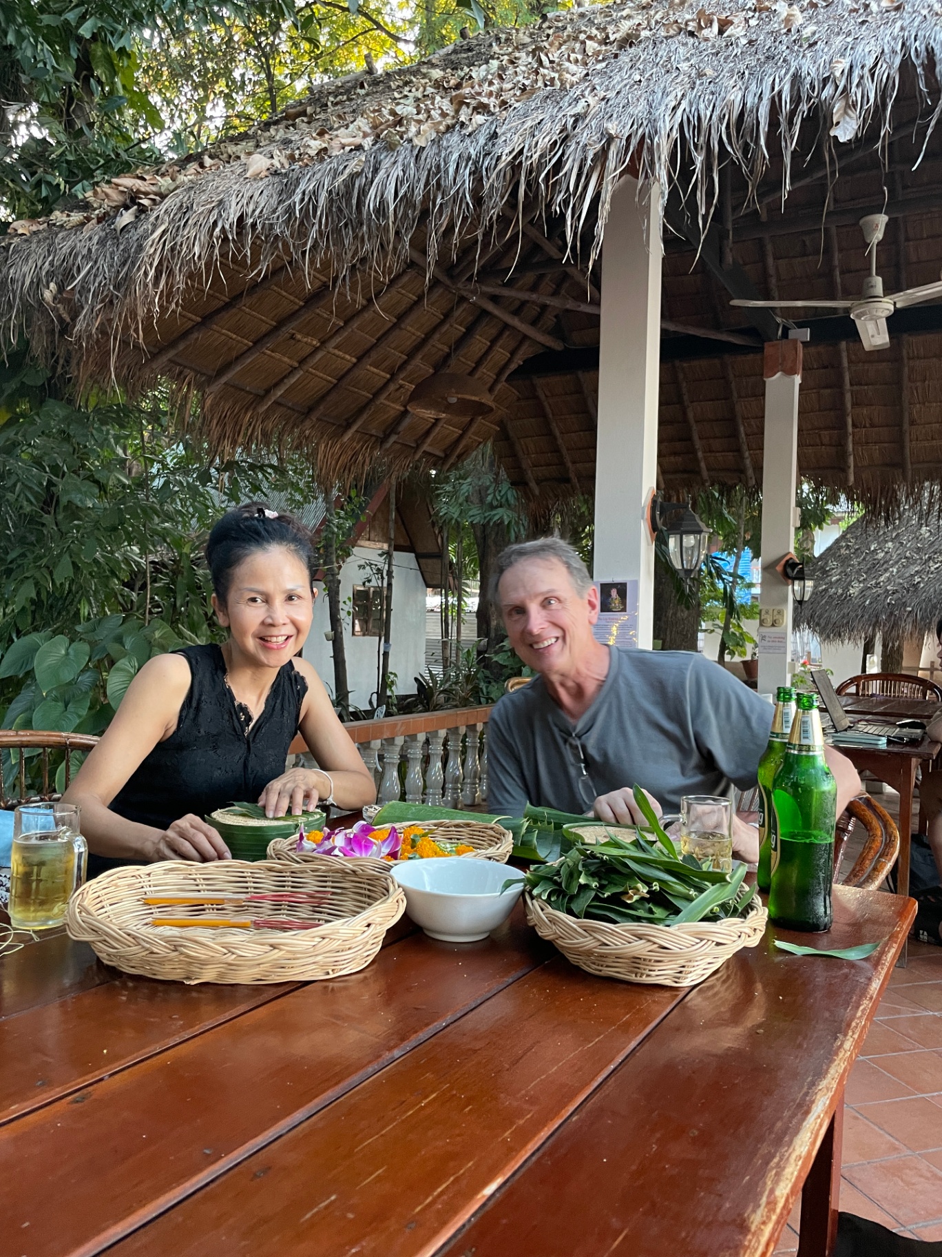 Ethan and Pranisa at a thatched-roof restaurant in Thailand
