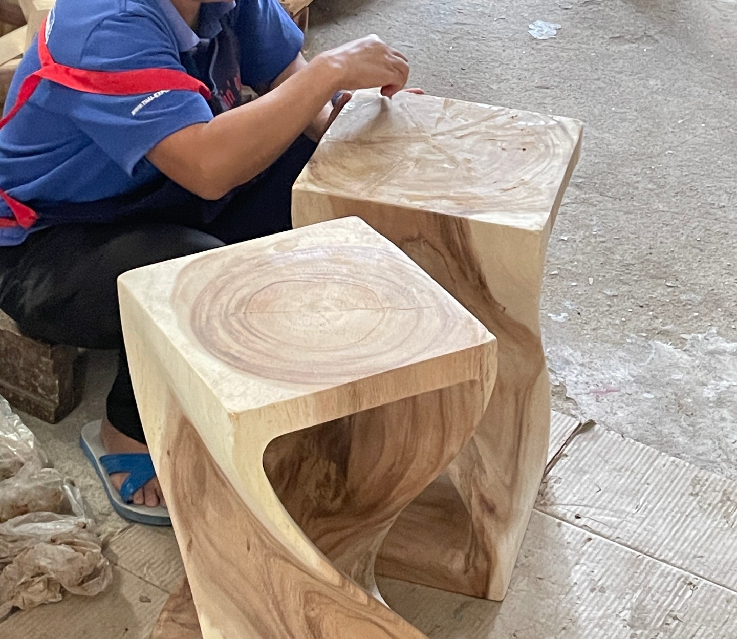 Artisan hand-finishing carved wooden stools in her workshop