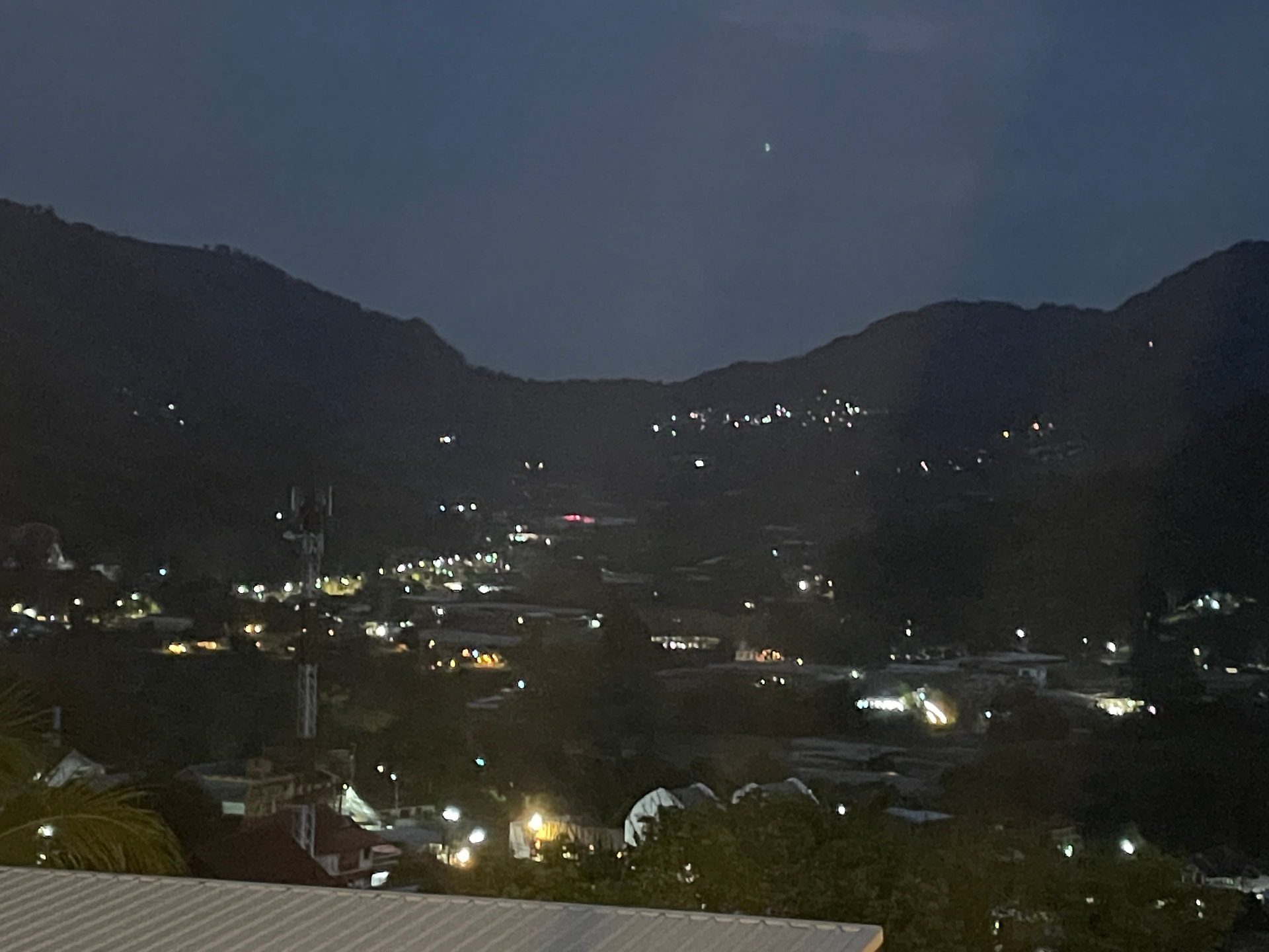 Village lights glowing beneath the mountains at night in northern Thailand