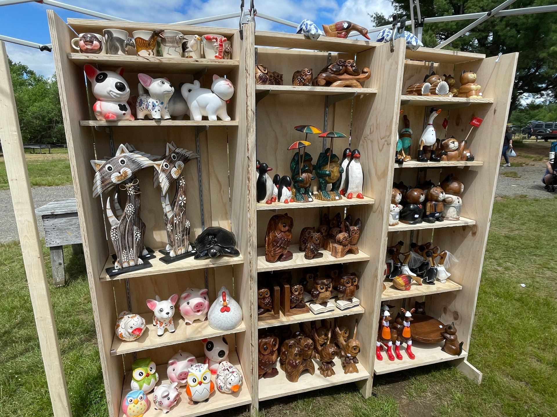 Shelves of hand-painted ceramics and hand-carved wooden animals at our market booth